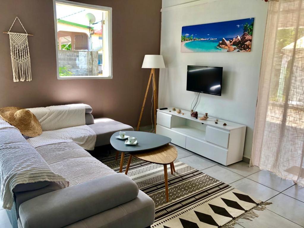 een woonkamer met een bank en een tv bij Zandoli Cottage in Les Galets