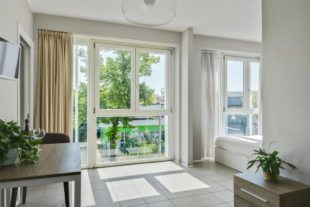 a living room with windows and a bed and a desk at MyPlace Padova Ospedale in Padova