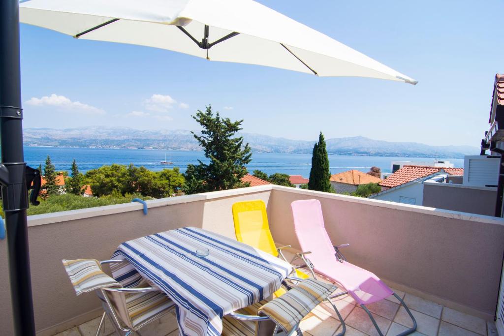 einen Balkon mit einem Tisch, Stühlen und einem Sonnenschirm in der Unterkunft Villa Tereza in Splitska