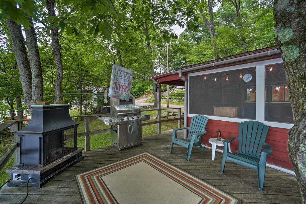 a screened in porch with a stove and two chairs at Riverfront Escape with Dock 19 Mi to Saratoga! in Lake Luzerne