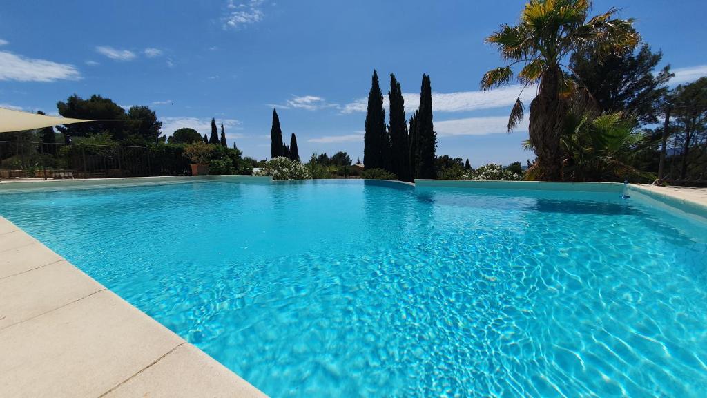 une grande piscine bleue avec des arbres en arrière-plan dans l'établissement Terres du Baguier, à Ceyreste