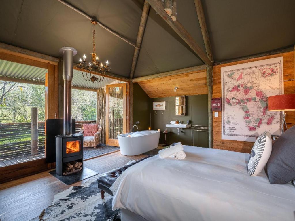 1 dormitorio con cama, bañera y chimenea en De Cango Farm en Oudtshoorn