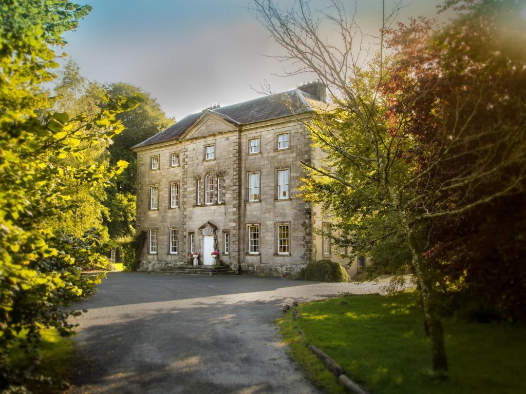 una vieja casa de piedra en medio de árboles en Roundwood House en Mountrath