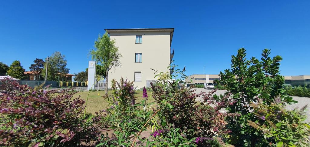 un edificio bianco con dei fiori davanti di Eco Rooms & Apartments a Voghera