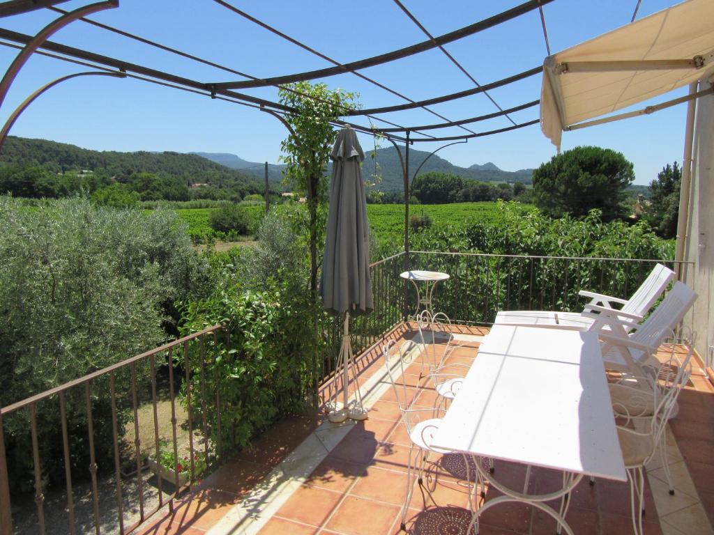 un patio avec une table et des chaises blanches sur un balcon dans l'établissement CHAMBRE D'HÔTE LE GRAND BARSAN, à Vaison-la-Romaine