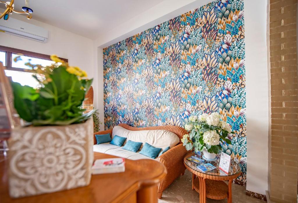 a living room with a couch and a floral wall at Agave Superior Rooms in San Vito lo Capo