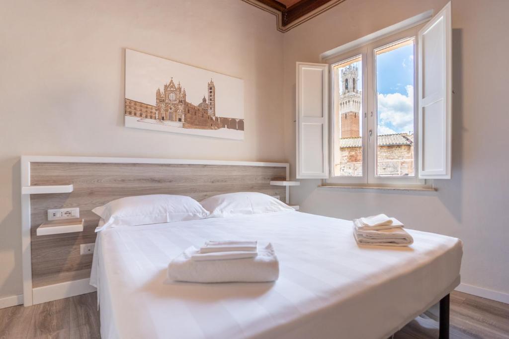 sypialnia z dużym białym łóżkiem i oknem w obiekcie Albergo Centrale w Sienie