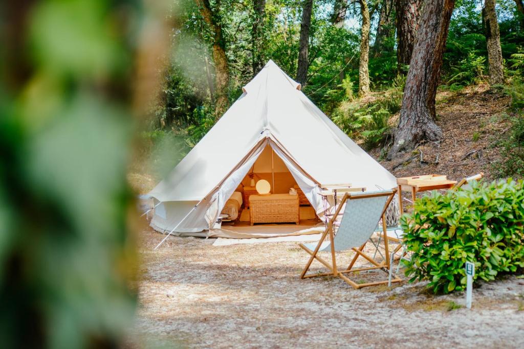 una tienda blanca con una silla delante en Cocooning Tipi - Seignosse en Seignosse