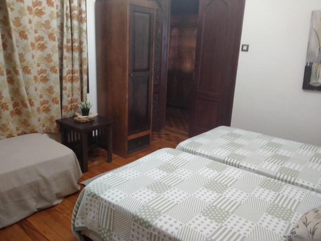 a bedroom with two twin beds and a table at Vilavella alojamiento de época in Redondela