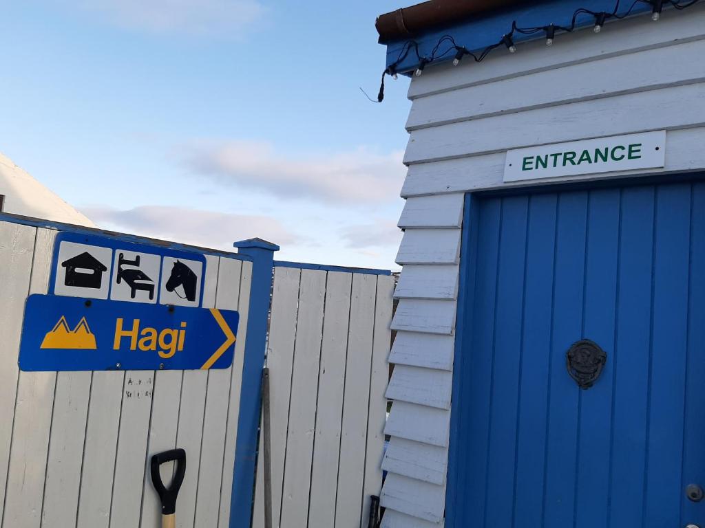 un edificio con un letrero de ayuda junto a un garaje en Hagi 1 Guesthouse en Aðaldalur