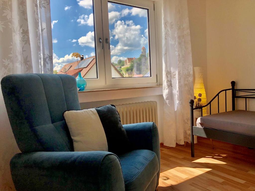 guest apartment niederalfingen في Hüttlingen: غرفة معيشة مع كرسي أزرق ونافذة