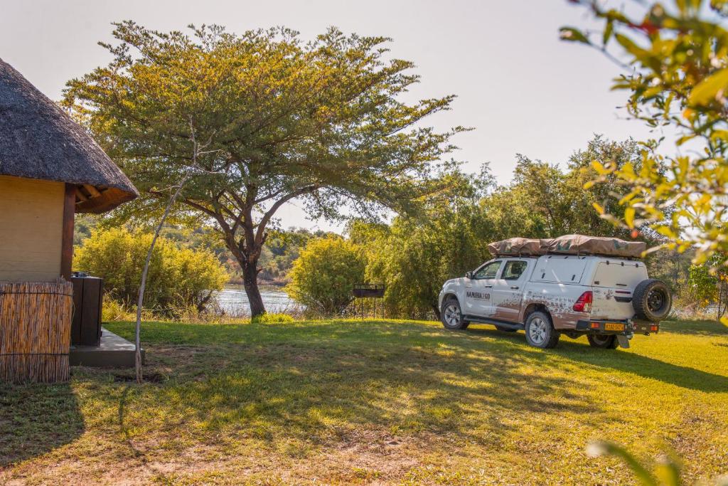 a white truck parked in a yard next to a house at Hakusembe River Campsite in Rundu