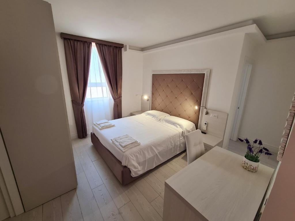 ein Schlafzimmer mit einem großen weißen Bett und einem Tisch in der Unterkunft L'Isola nel Parco Boutique Rooms & Apartments in La Maddalena