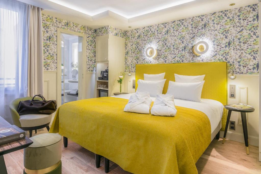 um quarto com uma grande cama amarela com um cobertor amarelo em Hotel Cambon em Paris