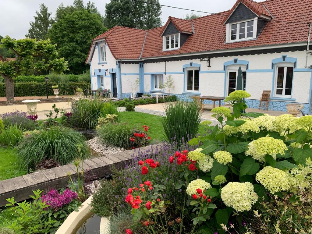 a garden in front of a house with flowers at Le Moulin de la Planquette in Cavron-Saint-Martin