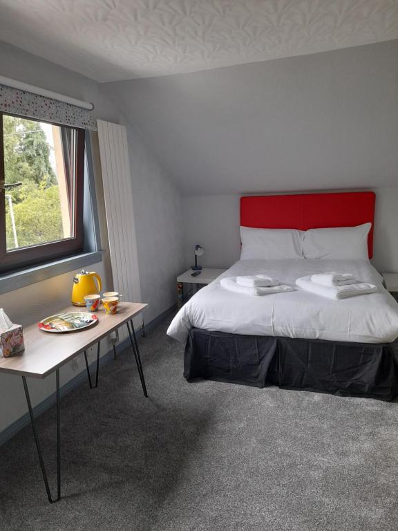 1 dormitorio con cama, mesa y ventana en Friars Bridge Guesthouse en Inverness