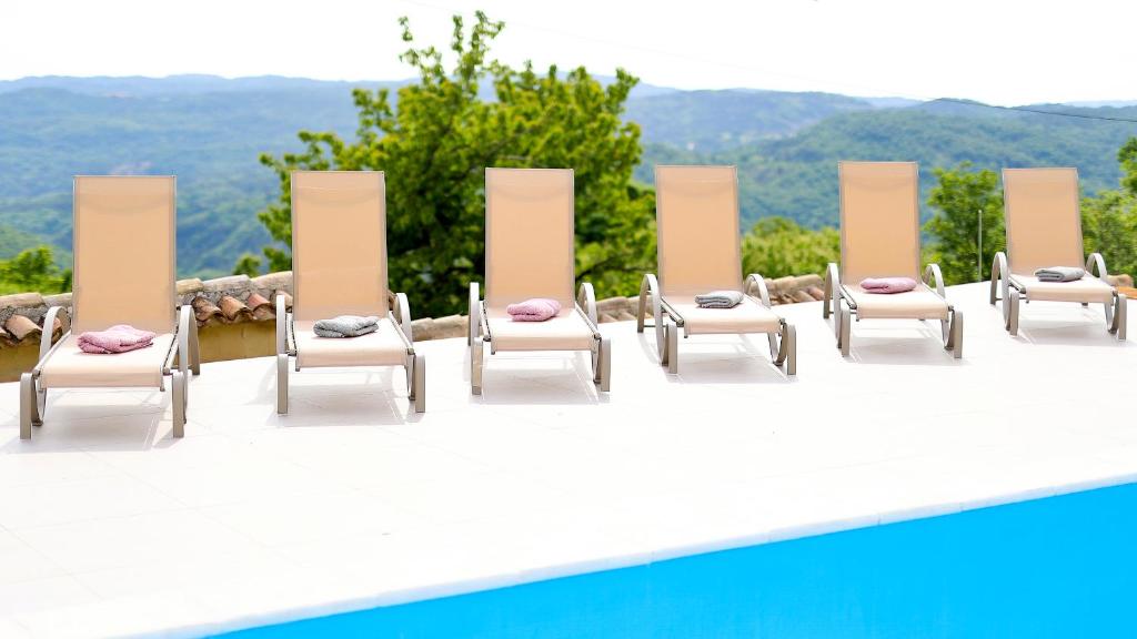 eine Reihe von Stühlen neben einem Pool in der Unterkunft Villa Kristina - Swimming pool, Dolenja Vas - Istra in Dolenja Vas