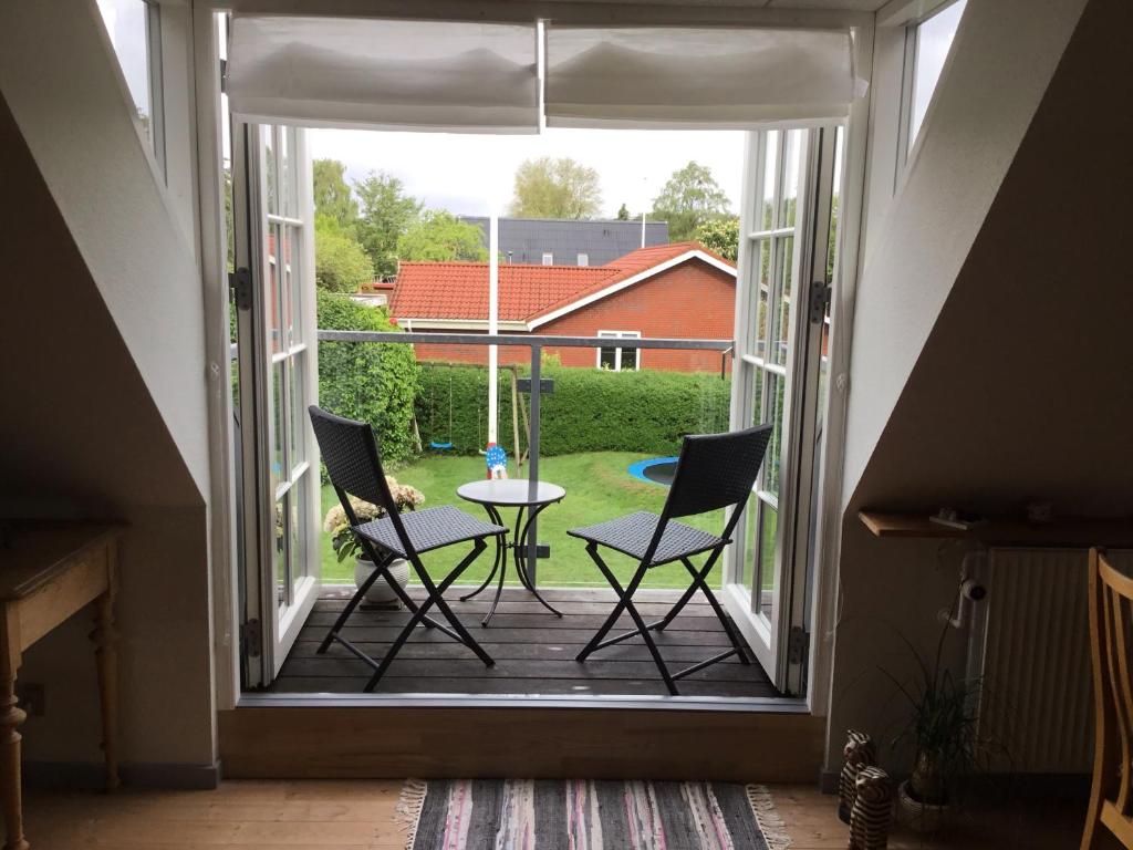 patio z 2 krzesłami i stołem w oknie w obiekcie Glejbjerg Bed and Breakfast w mieście Glejbjerg