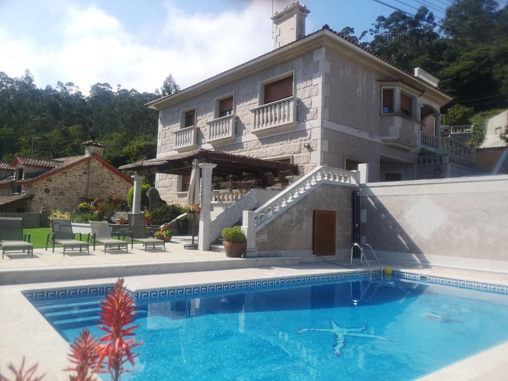 a villa with a swimming pool in front of a house at casa salvante in Moaña