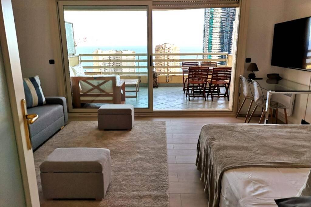 een slaapkamer met een bed en een woonkamer met een balkon bij Studio climatisé - belle vue mer-piscine in Beausoleil