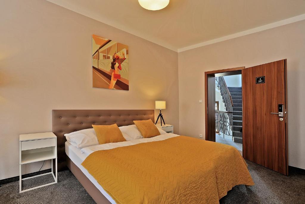 a bedroom with a bed with a orange bedspread at Hotel Pilgrim in Karlovy Vary
