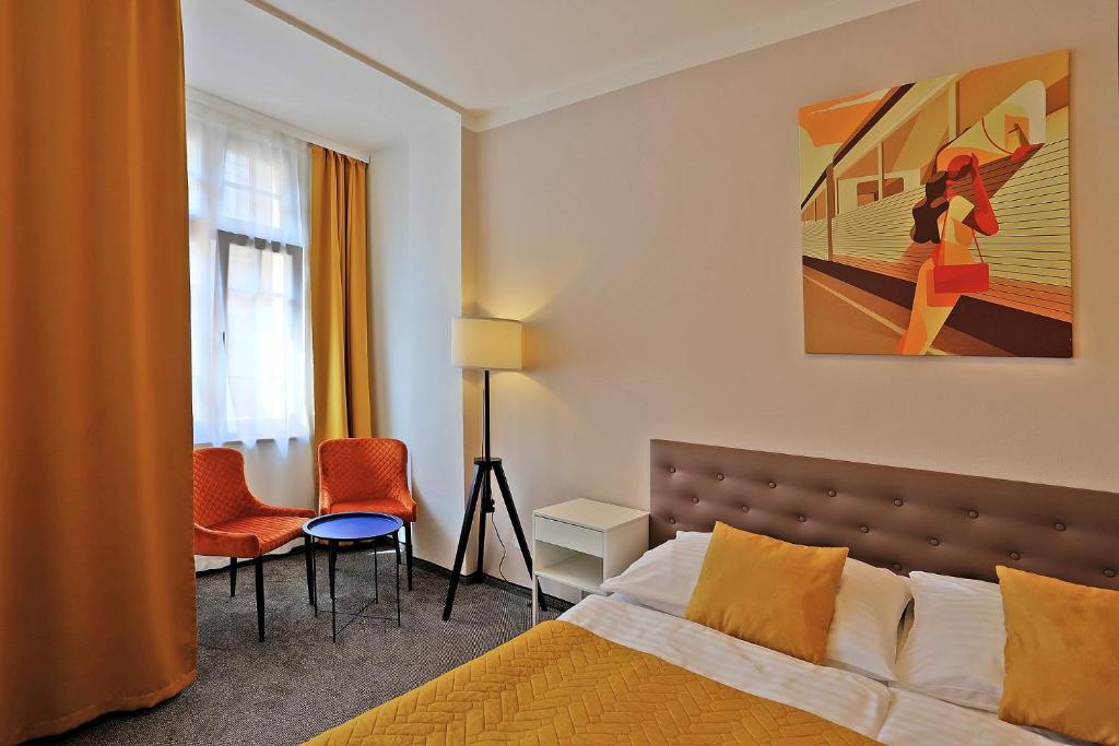 a bedroom with a bed and a painting on the wall at Hotel Pilgrim in Karlovy Vary