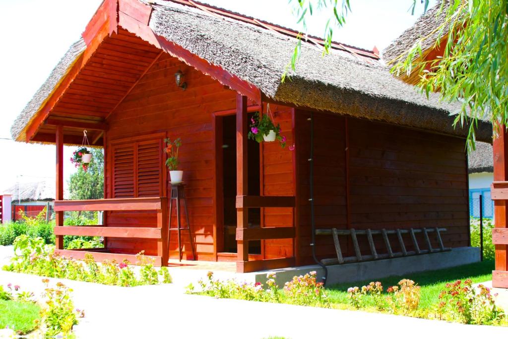 una pequeña casa de madera con techo de paja en Pensiunea La Tavi en Murighiol