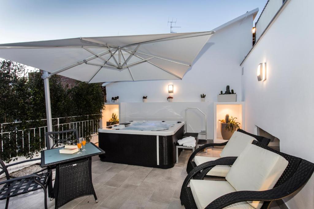 a patio with a tub and chairs and an umbrella at Magi House Relais in Sorrento