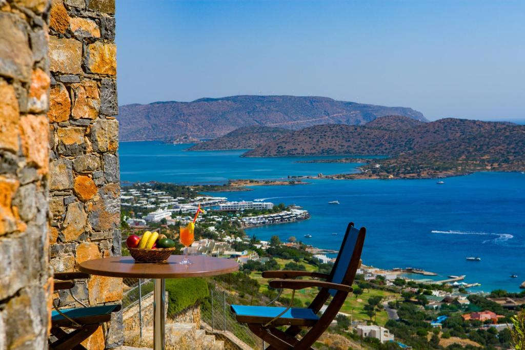 a table and chairs on a balcony with a view of the ocean at Athina Stunning Elounda View Apartment in Elounda