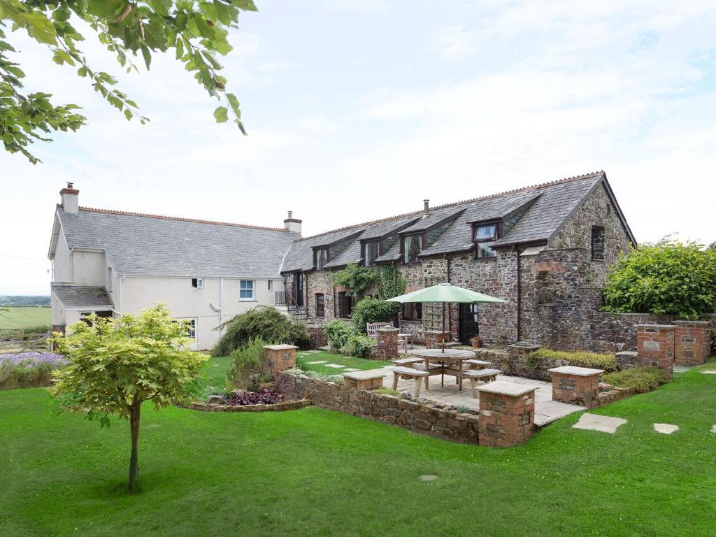 une maison en pierre avec une table de pique-nique dans la cour dans l'établissement Honey Bee Cottage, à Holsworthy