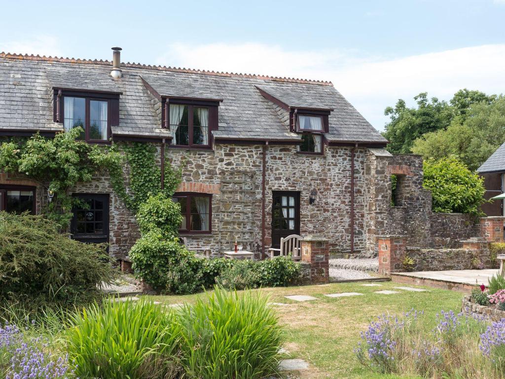 an old stone house with a garden in front of it at Greenfinch in Holsworthy