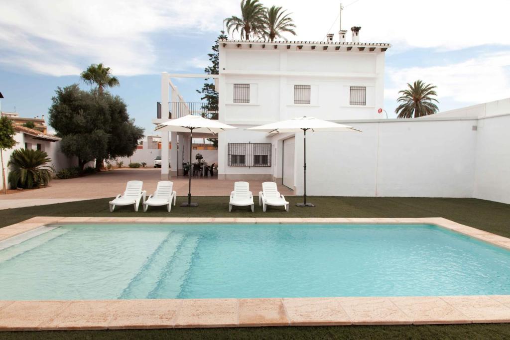 uma piscina com cadeiras e guarda-sóis em frente a uma casa em Villa Conchin Casa junto a Parque Natural em Alberique