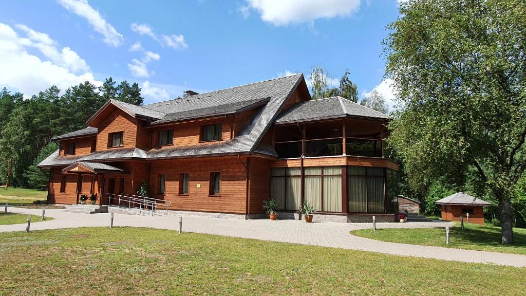uma grande casa de madeira com um telhado de gambrel em Pilnų namų bendruomenės apartamentai em Panara