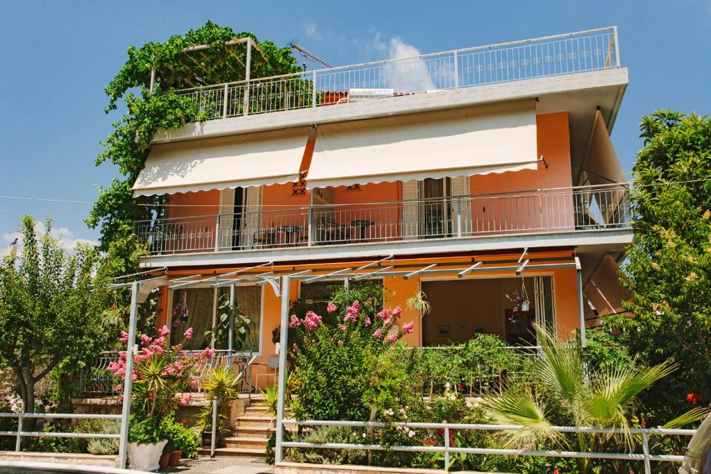 an orange house with a balcony and flowers at Hotel Loula Rooms and Apartments in Kamena Vourla
