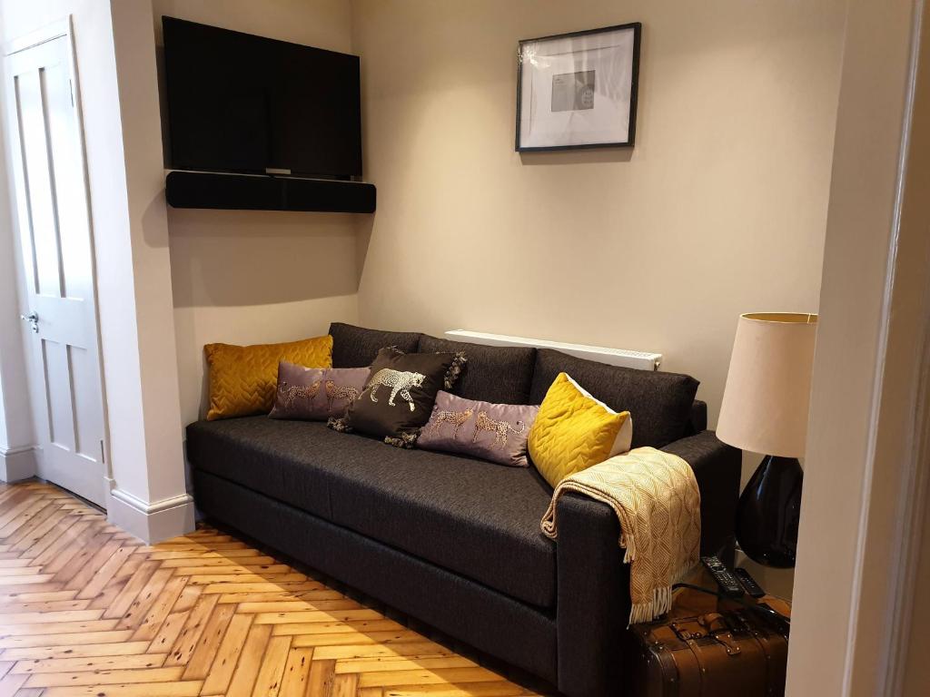 sala de estar con sofá negro con almohadas en St Paul's Studios apartment, en Londres
