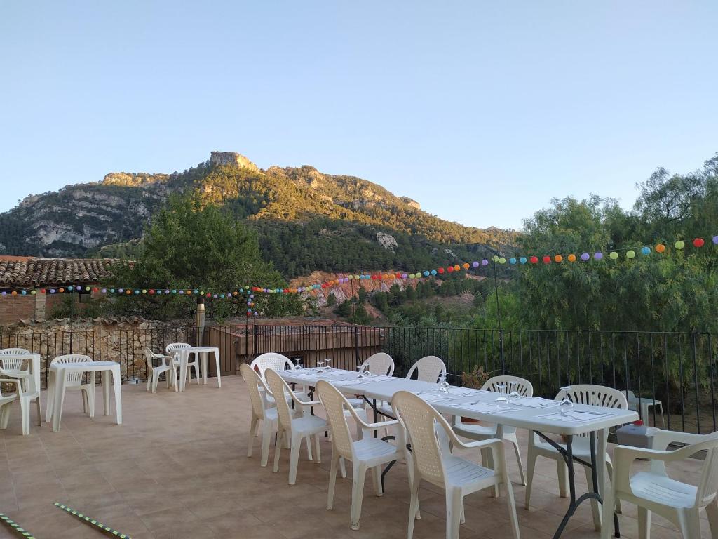 un patio con mesas y sillas blancas y una montaña en Alberg Ca La Jepa, en Prat de Comte