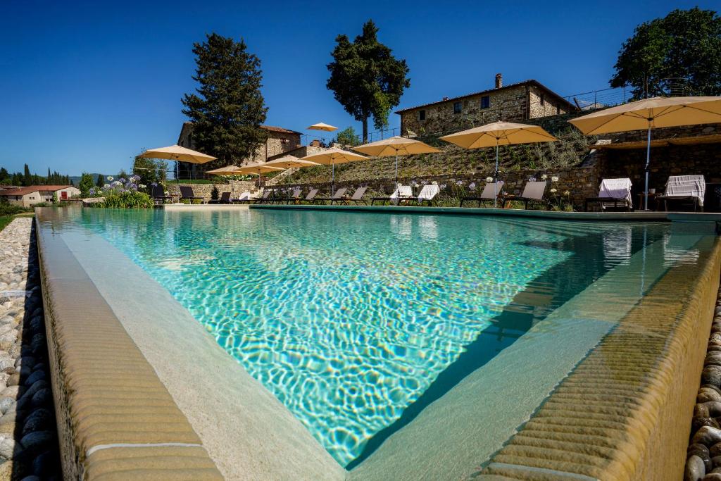 una grande piscina con sedie e ombrelloni di La Pietra Del Cabreo a Greve in Chianti