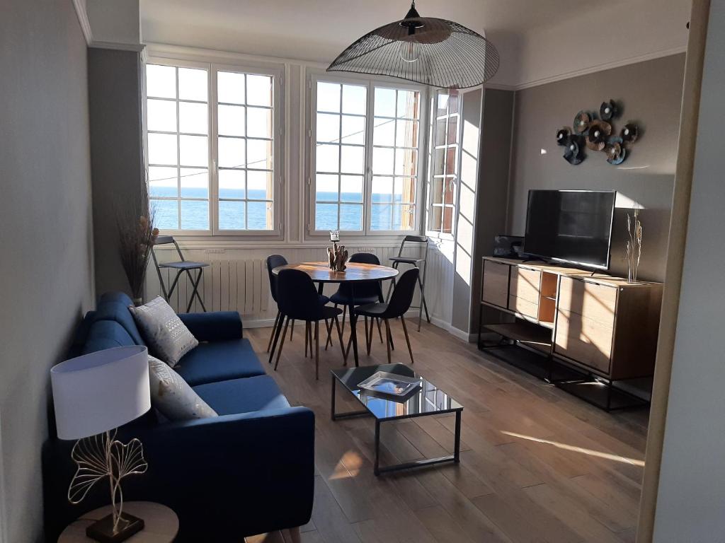 sala de estar con sofá azul y mesa en Au gré des marées, appartement face à la mer, classé 3 étoiles, en Ault