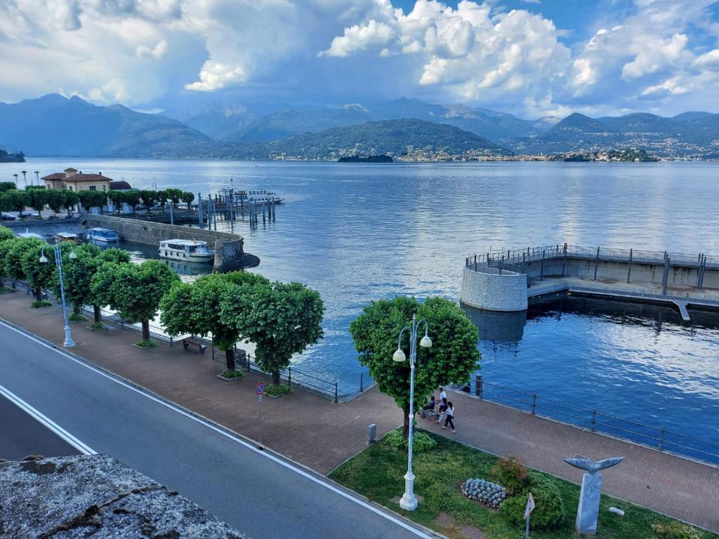 a view of a lake with a pier and a street at liberty lake house in Stresa