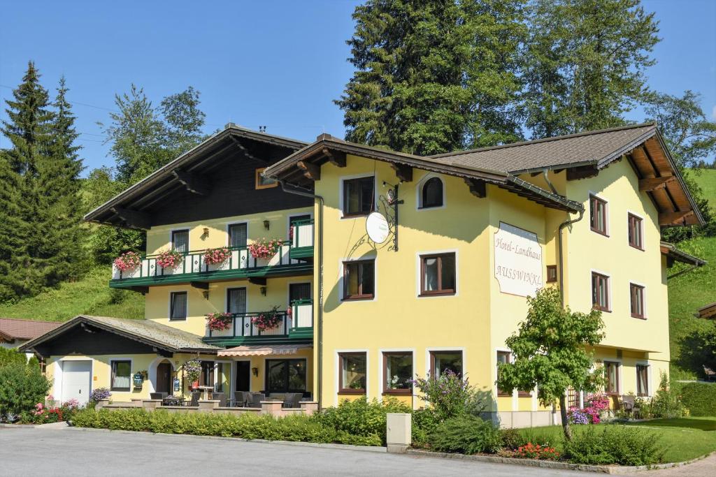 een geel gebouw met een zwart dak bij Hotel Landhaus Ausswinkl in Russbach am Pass Gschütt