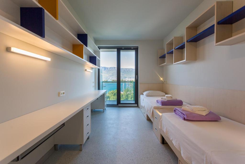 Zimmer mit 3 Betten und einem Schreibtisch mit Fenster in der Unterkunft Hostel BB in Split