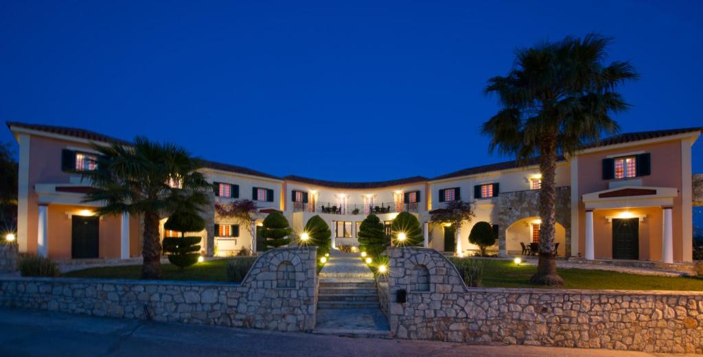 a large building with a stone wall and palm trees at Elanthi Village Apartments in Kalamaki