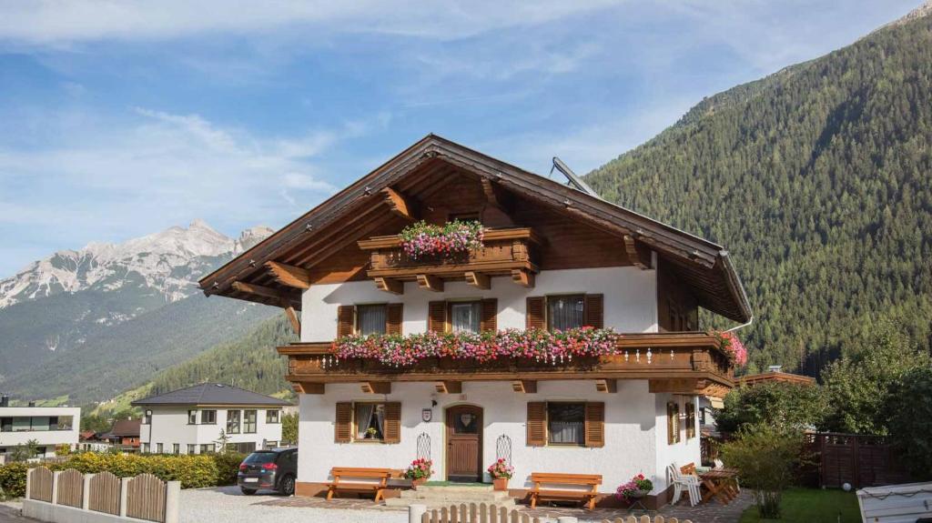 a house with flowers on the balcony with mountains at Ferienhaus Stubai in Neustift im Stubaital