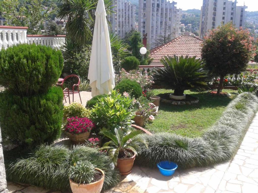 a garden with potted plants and a white umbrella at Milović apartmani in Igalo