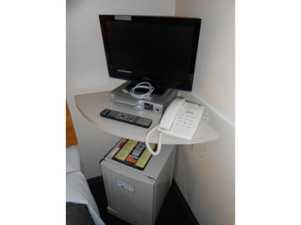 einen Schreibtisch mit einem Computer und einem Telefon darauf in der Unterkunft R&B Hotel Umeda East - Vacation STAY 40693v in Osaka