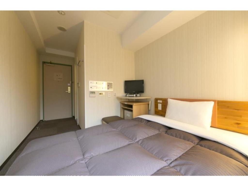 a bedroom with a bed and a desk with a television at R&B Hotel Umeda East - Vacation STAY 40694v in Osaka