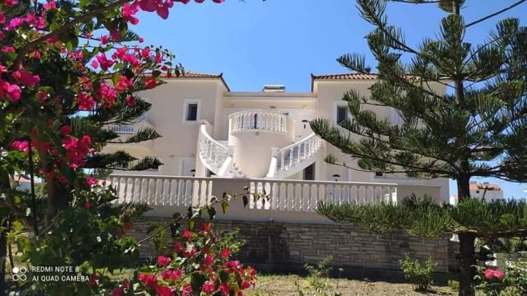 een groot wit huis met een balkon en bloemen bij Villa Vourda in Marathokampos