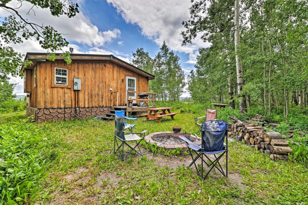 a cabin in the woods with chairs and a fire pit at Duck Lake Cabin Rental Near Glacier National Park! in Saint Mary