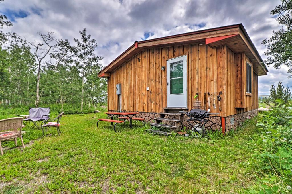 a wooden cabin with a picnic table and chairs at Cozy Duck Lake Cabin Near Glacier Natl Park! in Saint Mary