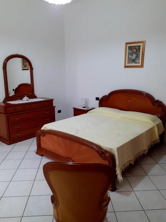 um quarto com uma cama, uma cómoda e um espelho em Casa Cesa em Selargius